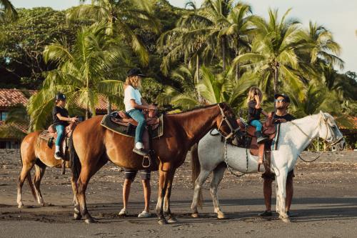 een groep mensen die paardrijden op het strand bij Hotel Playa Cambutal in Cambutal