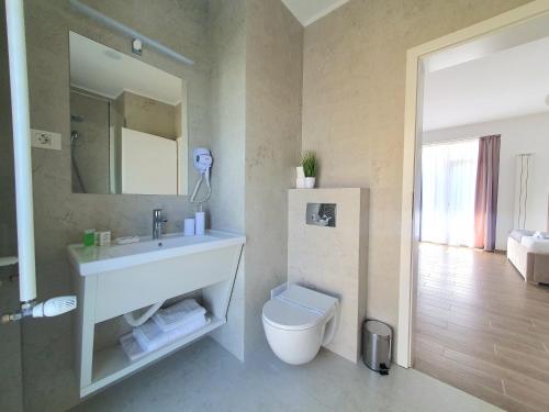 La salle de bains est pourvue d'un lavabo, de toilettes et d'un miroir. dans l'établissement MIANELLY Apartments Mamaia Nord, à Mamaia Nord – Năvodari