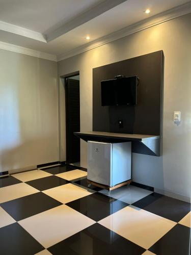 a room with a television and a checkered floor at Chapada Park Pousada e Restaurante in Chapada dos Guimarães
