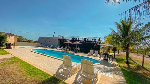 - une piscine avec 2 chaises et une table dans l'établissement Pousada e Restaurante Valle dos Ventos, à Chapada dos Guimarães