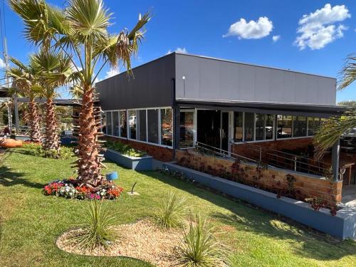 a building with a palm tree in front of it at Pousada e Restaurante Valle dos Ventos in Chapada dos Guimarães