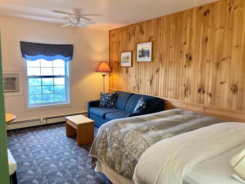 a bedroom with a bed and a couch and a window at Castle Rock Country Inn in Ingonish Beach