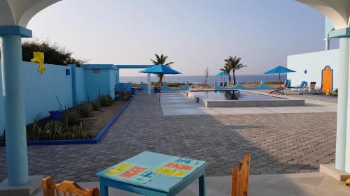 a patio with a table and a beach with umbrellas at Villa Star of the Sea in Barra de Navidad