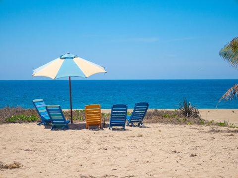 a group of chairs and an umbrella on the beach at Villa Star of the Sea in Barra de Navidad