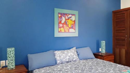 a blue bedroom with a bed and a painting on the wall at Villa Star of the Sea in Barra de Navidad