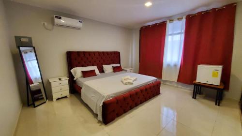 una camera da letto con un grande letto con tende rosse di Habitaciones AlojaT MIMOS diagonal al hotel oro verde a Machala
