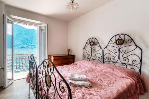 a bedroom with a bed with a pink bedspread and a window at Da Flora Wonderful Lakefront View in Colonno