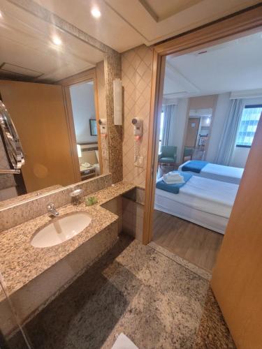 Un baño con lavabo, espejo y cama. en Flat Lets Idea Brasília Hotel By Rei dos Flats, en Brasilia