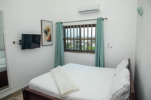 um pequeno quarto com uma cama e uma janela em Résidences Inaya em Cotonou