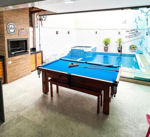 a pool table in a room with a swimming pool at Piscina com ofurô/Churrasqueira/Sinuca e Ping Pong in Caraguatatuba