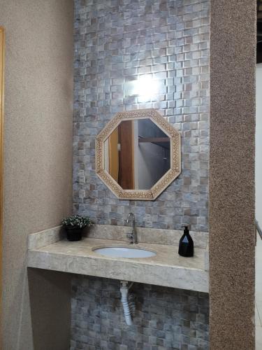 a bathroom with a sink and a mirror at Casa Temporada Nosso Recanto Piscina aquecimento Solar in Olímpia