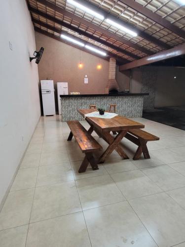 a wooden table and benches in a room with a counter at Casa Temporada Nosso Recanto Piscina aquecimento Solar in Olímpia