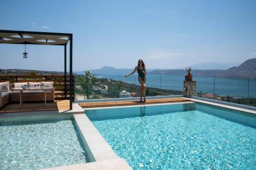 a woman is standing next to a swimming pool at Villa Damant in Pithárion