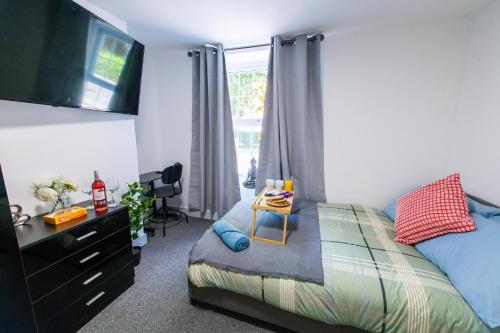 a bedroom with a bed with a dresser and a television at Maidstone High St - Deluxe Ensuite Rooms - Fast Wi-Fi in Kent