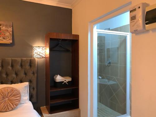 a bedroom with a bed and a shower with a glass door at LuxuryAirportLodge near OR TAMBO in Kempton Park