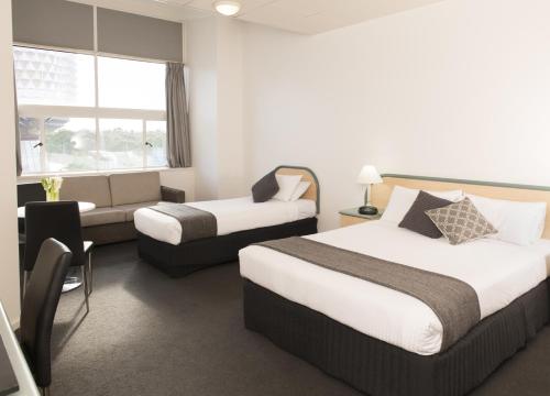 a hotel room with two beds and a couch at Adelaide Riviera Hotel in Adelaide