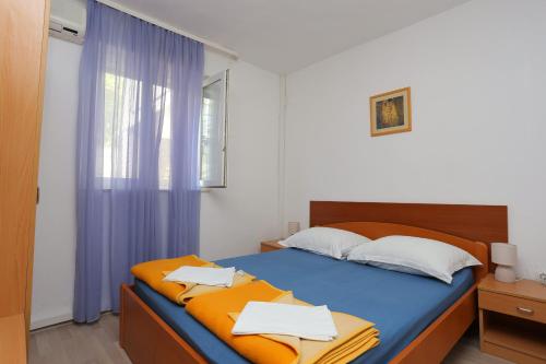sypialnia z łóżkiem z niebieską pościelą i oknem w obiekcie Double Room Tucepi 5263f w Tučepi