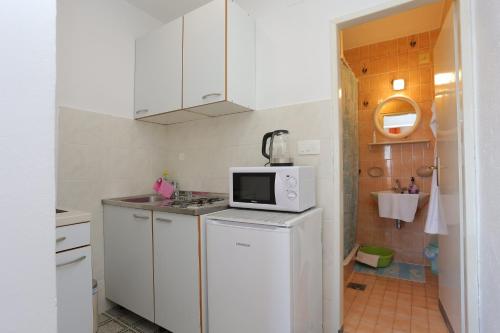 a kitchen with white cabinets and a microwave at Apartments and rooms with parking space Tucepi, Makarska - 5263 in Tučepi
