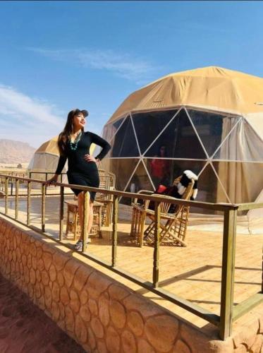 a woman standing next to a fence in front of a tent at orbit camp 2 in Wadi Rum