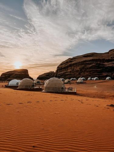 a group of tents in the desert with the sunset at orbit camp 2 in Wadi Rum