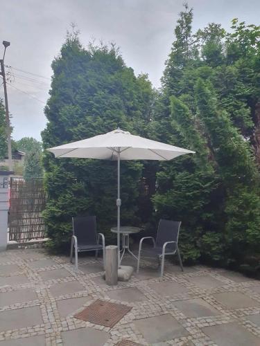 a table and two chairs under an umbrella at Pokoje ze wspólną łazienką i kuchnią w centrum Starachowic in Starachowice