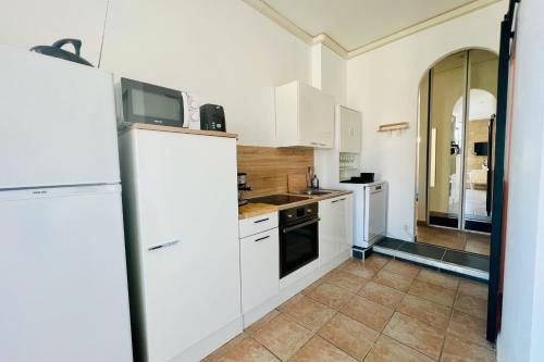 a kitchen with white appliances and a tile floor at Terrasse du Port -Appartement 2 chambres avec vue sur le canal in Le Grau-du-Roi