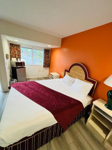 a bedroom with a large bed with an orange wall at Colonel Williams Resort and Suites in Lake George