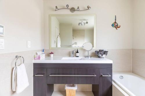 a bathroom with a sink and a mirror and a tub at Quiet and cosy in Waikanae