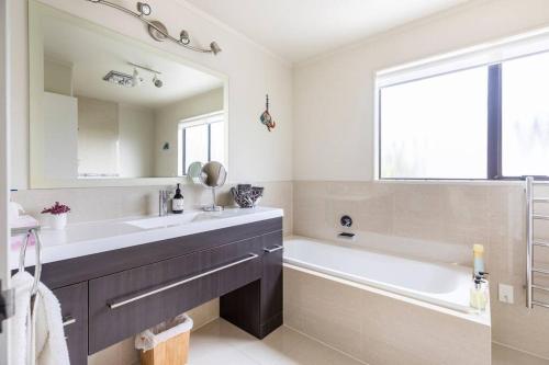 a bathroom with a sink and a tub and a mirror at Quiet and cosy in Waikanae
