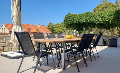Une table et des chaises en bois sont disponibles sur la terrasse. dans l'établissement Seaside holiday house Prizba, Korcula - 21583, à Blato