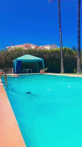 une piscine avec une tente bleue en arrière-plan dans l'établissement Villas avec Piscine & Jardin Privés, à Marrakech