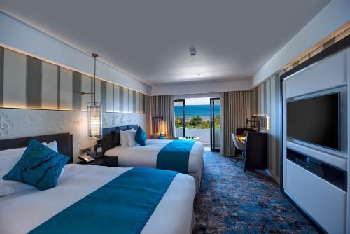 a hotel room with two beds and a flat screen tv at InterContinental Muscat by IHG in Muscat