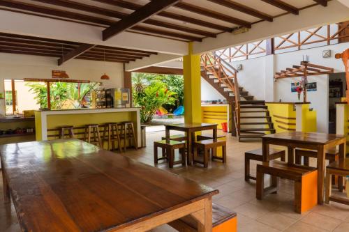 a restaurant with wooden tables and chairs and stairs at Pagalù Hostel in Puerto Viejo