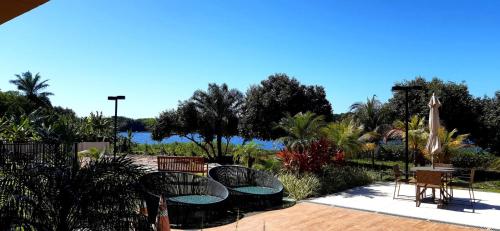 a patio with tables and chairs and a view of the water at Apartamento em Guarajuba - Condomínio Paraíso dos Coqueiro in Guarajuba