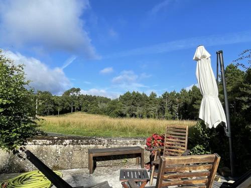 un patio con sombrilla, silla y mesa en Holiday home with tennis court in Montcl ra, en Frayssinet-le-Gélat