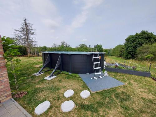 a small shed with a ladder in a yard at Holiday home in Noiseux with fenced garden in Noiseux