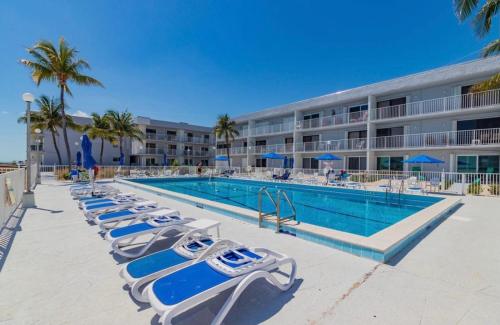 a pool with lounge chairs next to a hotel at Your Happy Place ON THE BEACH! in Key Colony Beach