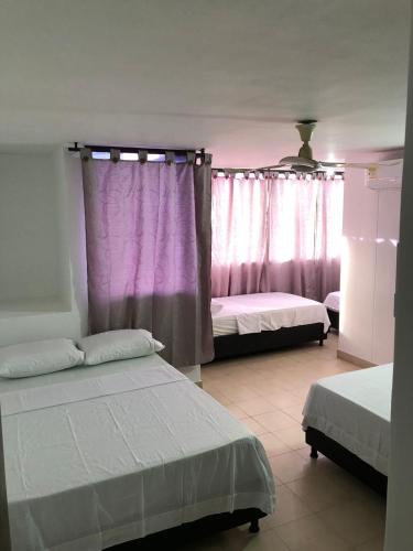 1 Schlafzimmer mit 2 Betten und rosa Vorhängen in der Unterkunft Apartamento Santa Marta - El Rodadero in Gaira