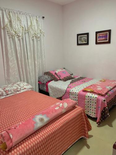 three beds in a room with pink sheets at Balcones de la Casona in Guatapé