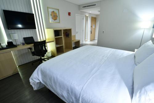 a bedroom with a large white bed and a desk at Holiday Inn Express Asuncion Aviadores by IHG in Asuncion