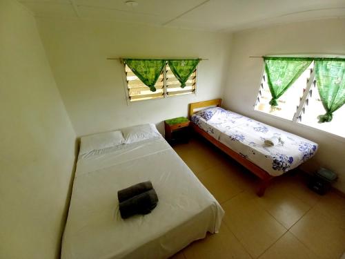 a small bedroom with two beds and two windows at Philomena's Lodge in Douane