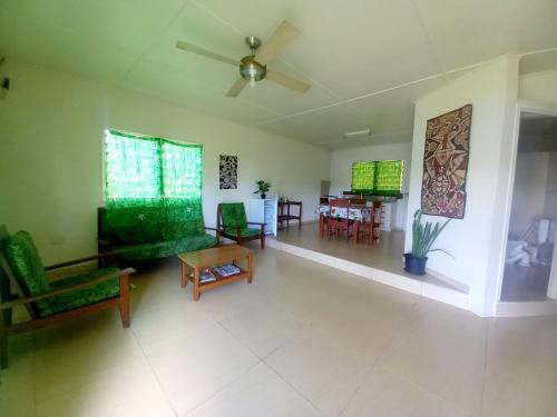 a living room with green furniture and a dining room at Philomena's Lodge in Douane