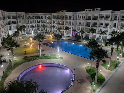 an empty pool in front of a hotel at night at COSTA BEACH Lux Family Apartment with Pools in Bouznika