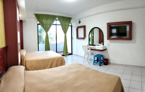 Habitación de hotel con 2 camas y espejo en Hotel Real del Quijote a sólo 50 metros de la playa, en Tecolutla