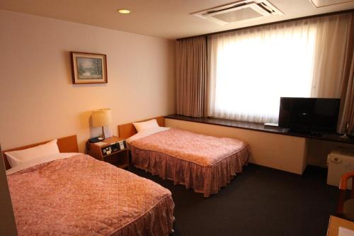 a hotel room with two beds and a window at Shingu Central Hotel in Shingu