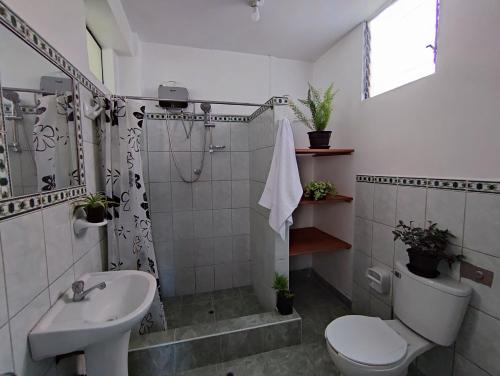 y baño con lavabo, aseo y ducha. en Casa QENTE, en Cusco