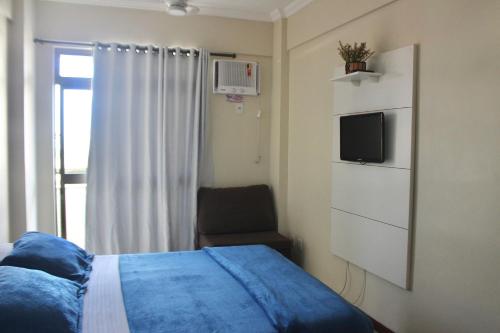 1 dormitorio con 1 cama, TV y silla en Aconchegante 3 quartos na Prainha, en Arraial do Cabo