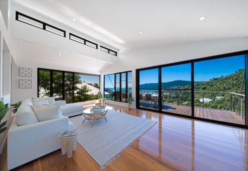 Una sala de estar con un sofá blanco y grandes ventanales. en Seaview On Airlie, en Airlie Beach