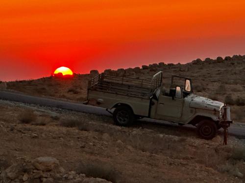 a truck driving down a road with a sunset in the background at Petra Desert Dream Hotel in Wadi Musa