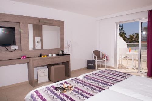 a bedroom with a bed and a desk and a television at New Famagusta Hotel & Suites in Ayia Napa
